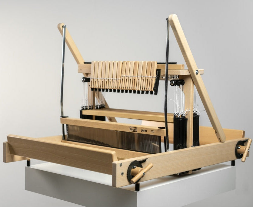 Wooden weaving loom with blue fabric on a plain background