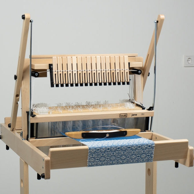 Wooden weaving loom with blue fabric on a plain background