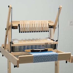 Wooden weaving loom with blue fabric on a plain background