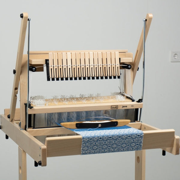 Wooden weaving loom with blue fabric on a plain background